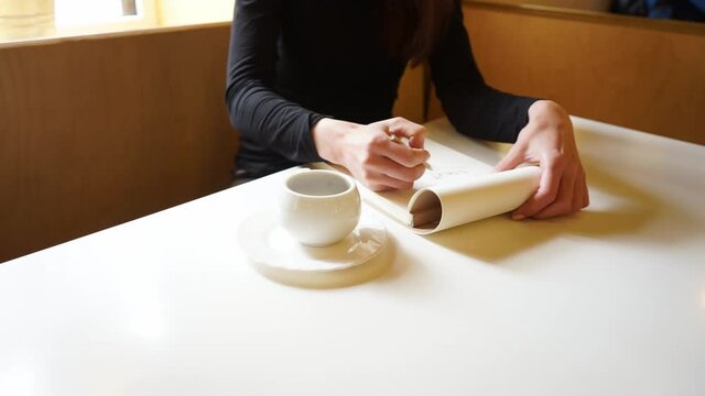 a Hand of a girl draws in sketchbook with a pencil in a cafe, a cup of coffee on the table, Camera shifting in