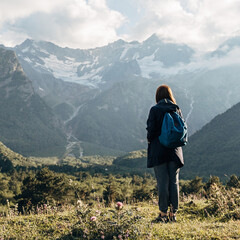 girl tourist in the mountains looks at the mountains