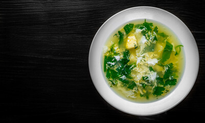Green Sorrel soup in white plate on black wooden table background