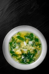 Green Sorrel soup in white plate on black wooden table background