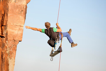Rock climber and photographer Norbert Frank ascending a rock with a rope