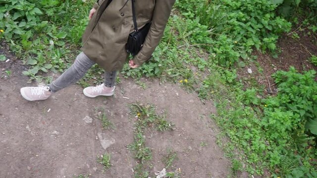 a girl stands rubbing her hands than walk along a path in a field