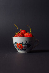 little cute cup with fresh strawberries on black background. High quality photo