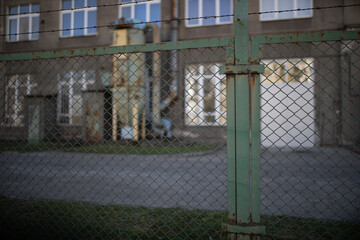widok na stary magazyn z zewnątrz przez ogrodzenie z metalowej siatki z drutem  © sandrqa