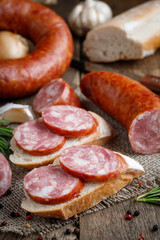Sandwich with smoked sausage. Dry-cured sausage, bread and spices on a wooden table.
