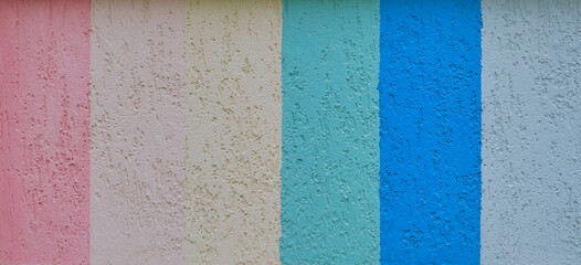 Texture of a wall covered with seven multicolored vertical stripes of textured stucco as a...