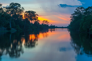 Sunset along the banks of the Amazon river. The tributaries of the Amazon traverse the countries of...