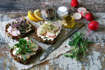 Fototapeta na wymiar Open sandwiches with white cheese, radish and microgreens. Healthy toast for breakfast or snack.