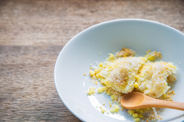 Close up homemade mung bean rice-crepe in a white plate with wooden spoon on rustic wooden table.