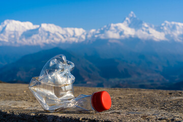 Сrumpled empty plastic bottle on the background of a Annapurna mountain range, Himalaya....