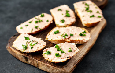 
Chicken pate on toast with fresh parsley on a cutting board on a stone background