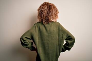 Beautiful african american woman with curly hair wearing casual sweater over white background...