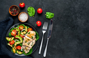 
Grilled chicken breast and grilled avocado salad with cherry tomatoes, spinach, in a black plate on a stone background 
with copy space for your text