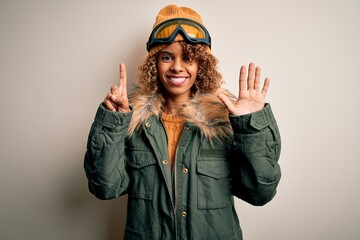 Young african american skier woman with curly hair wearing snow sportswear and ski goggles showing and pointing up with fingers number six while smiling confident and happy.