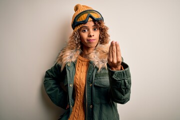 Young african american skier woman with curly hair wearing snow sportswear and ski goggles Doing Italian gesture with hand and fingers confident expression