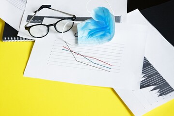 End of pandemic coronavirus and isolation. Used crumpled medical mask against glasses and chart for reducing incidence of morbidity and mortality.