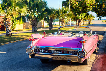 Old vintage pink american car parked near the beach on the street of Varadero city, Cuba