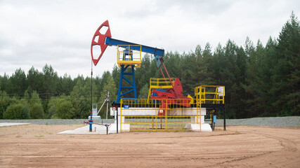 Fototapeta na wymiar Industrial oil pump jack working and pumping crude oil for fossil fuel energy with drilling rig in oil field. Balancing drive rod pumps oil rocker. Equipment for wellhead connection oil well.
