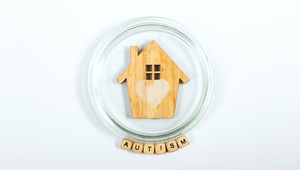 Autism text cubed under a wooden house in a protective glass circle