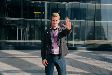 A young European man shows a hand sign prohibited. Stop the danger ahead.