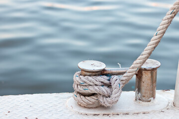 Rope tied on the stainless steel pollard on the deck of metal boat.