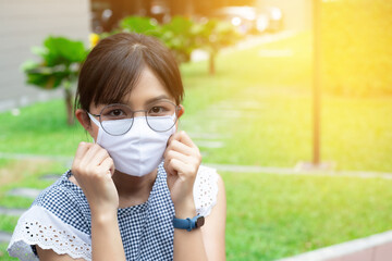 Portrait of Asian woman using surgical mask for protecting COVID-19 or epidemic disease, when go outside.