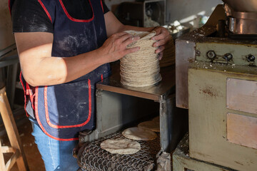 La mujer está juntando las tortillas de maíz  que han salido de la maquina.