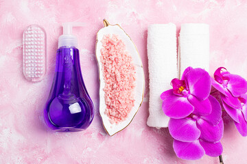 Plakat Spa treatment wellness concept. Natural spa cosmetics products, accessories, soap, sea salt, massage brush, tropic flower on pink background. Spa background flat lay. Top view