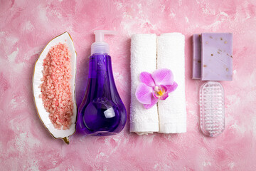 Fototapeta na wymiar Spa treatment wellness concept. Natural spa cosmetics products, accessories, soap, sea salt, massage brush, tropic flower on pink background. Spa background flat lay. Top view