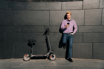 Man with smartphone and electric scooter standing near modern business center