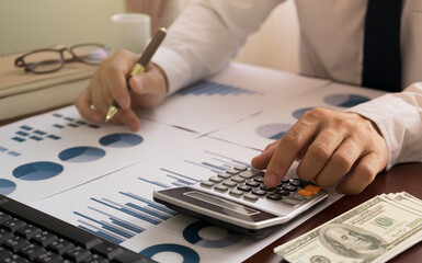 Obraz na płótnie Canvas Businessman using calculator and Analyzing Profit data graph financial