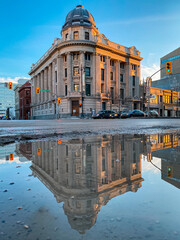 A heritage building in Winnipeg, Manitoba (Canada) is reflected in a water puddle
