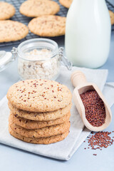 Fototapeta na wymiar Healthy oatmeal and red quinoa cookies on table and cooling rack served with milk, vertical