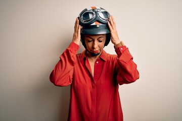 Middle age motorcyclist woman wearing motorcycle helmet over isolated white background suffering from headache desperate and stressed because pain and migraine. Hands on head.