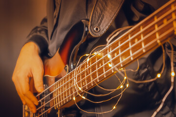 Man playing electric bass guitar blurred background with beautiful bokeh.