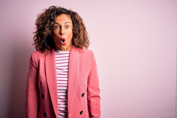 Middle age beautiful businesswoman wearing elegant jacket over isolated pink background afraid and shocked with surprise expression, fear and excited face.