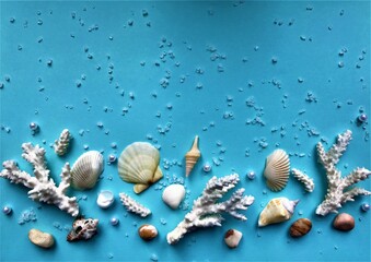 White coral twigs, several small shells, pebbles, scattered white crystals and pearls contrast on a bright turquoise background with space for text