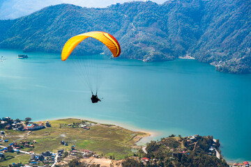 Paragliding in Nepal. Paraglider on the background of Phewa Lake, Pokhara city and surrounding villages. Stock photo.