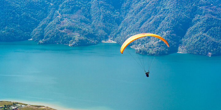 Paragliding in Nepal. Paraglider on the background of Phewa Lake, Pokhara city and surrounding villages. Stock photo.
