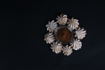 meringues and a bowl of cinnamon powder isolated on black background flat lay
