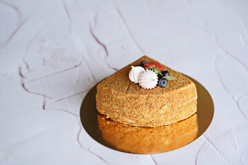 a quarter of honey puff cake on a white background decorated with marshmallows and fresh berries