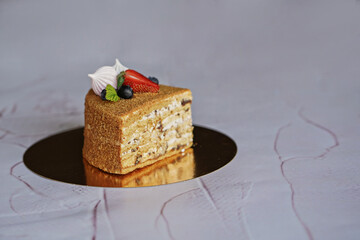 a slice of honey cake cut on a white background on a dark background decorated with fresh berries