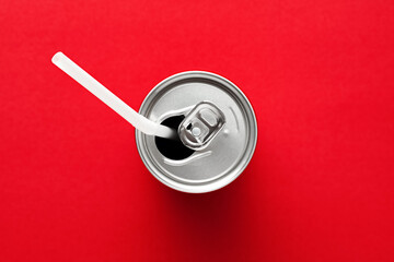 Aluminum drink or beverage can with straw on red background