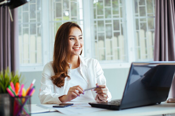 happy young cheerful business woman at home office working on laptop