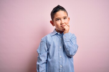 Young little boy kid wearing elegant shirt standing over pink isolated background with hand on chin...