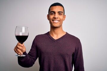Handsome african american sommelier man tasting glass of red wine over white background with a happy face standing and smiling with a confident smile showing teeth