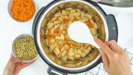 Multi cooker recipe. Cooking vegetables. Carrot, potatoes, lentils and some ingredients close up in a pot, view from above