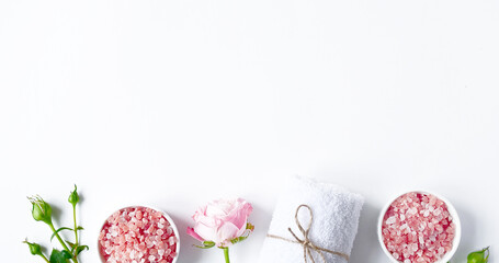 Spa flatlay composition. Sea salt in jar, towel, flower on white background. Top view, copyspace, banner. Daily care concept, relax and rest, bath procedure