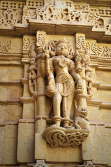 figure sculpture of a woman in stone on a bas-relief wall of a temple, India