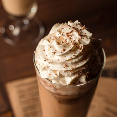 Cold coffee latte in glass with whipped cream and grated chocolate on the top.   Closeup.